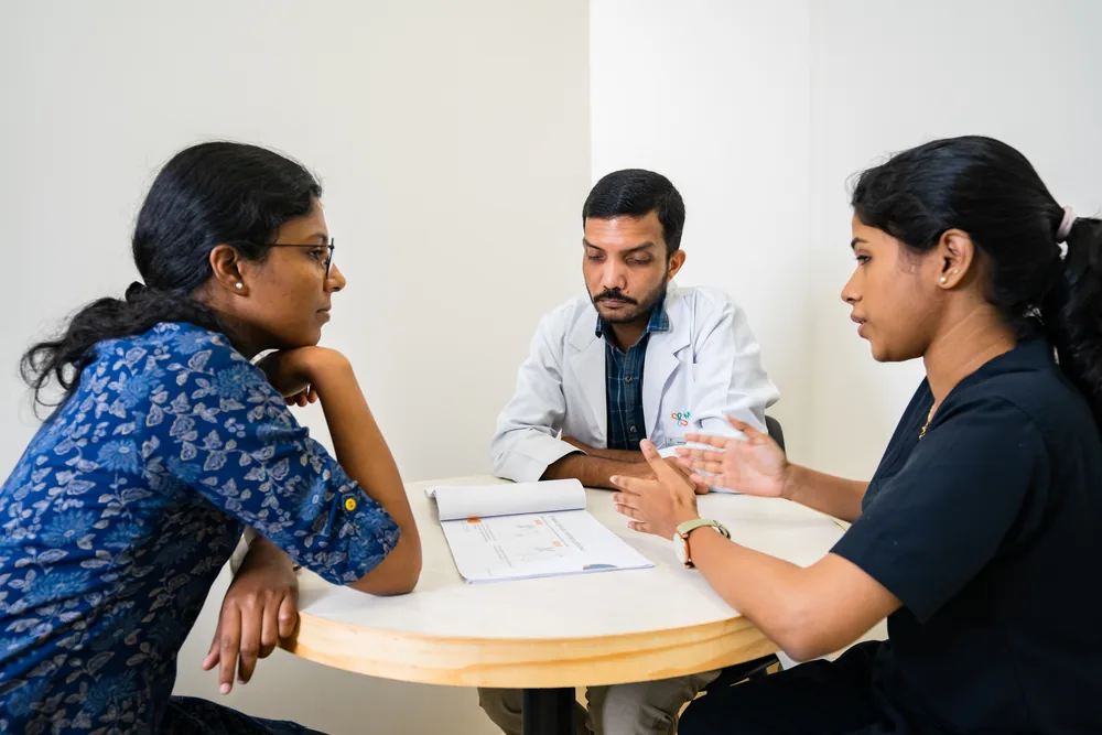 A doctor and a physiotherapist going through notes with a patient at a table