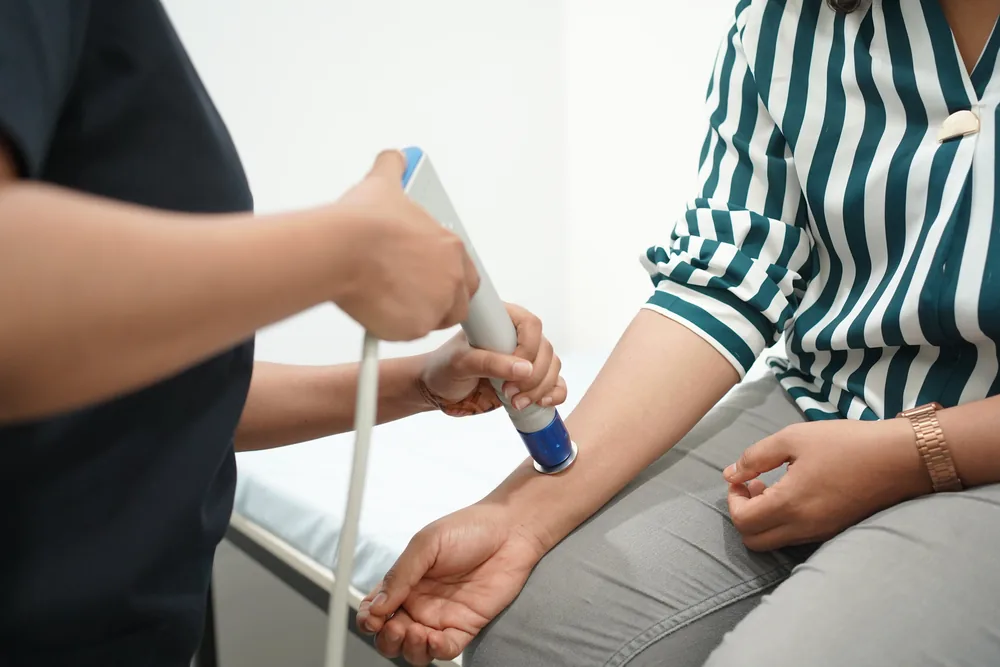 A shockwave therapy applicator being used on a patient's arm