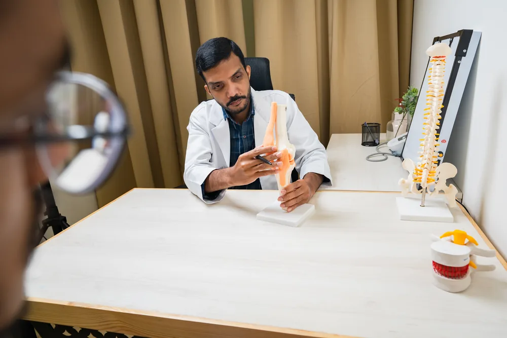 A doctor holding a spine model during a consultation
