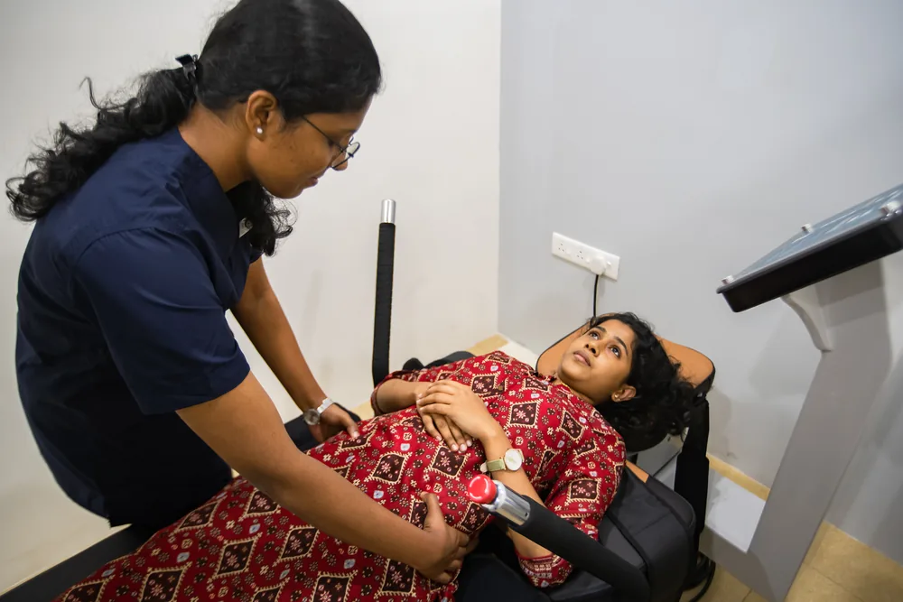 A patient on a spinal decompression system with a physiotherapist beside them