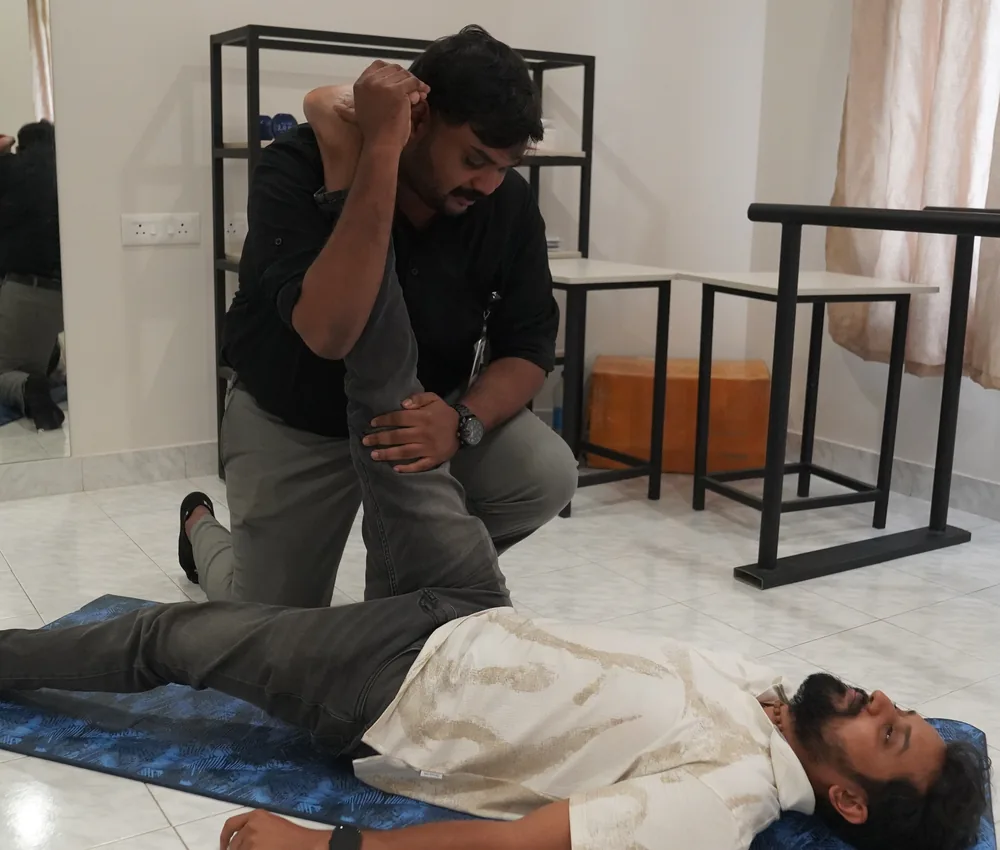 A physiotherapist stretching a patient's leg on a mat