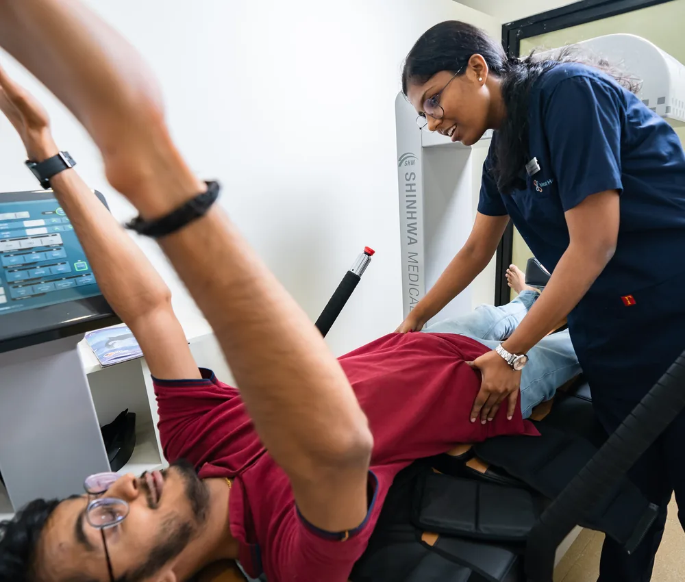 A patient on a spinal decompression system with a physiotherapist beside them
