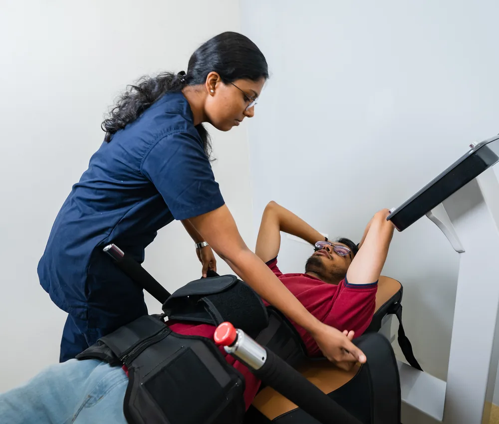 A patient on a spinal decompression system with a physiotherapist beside them