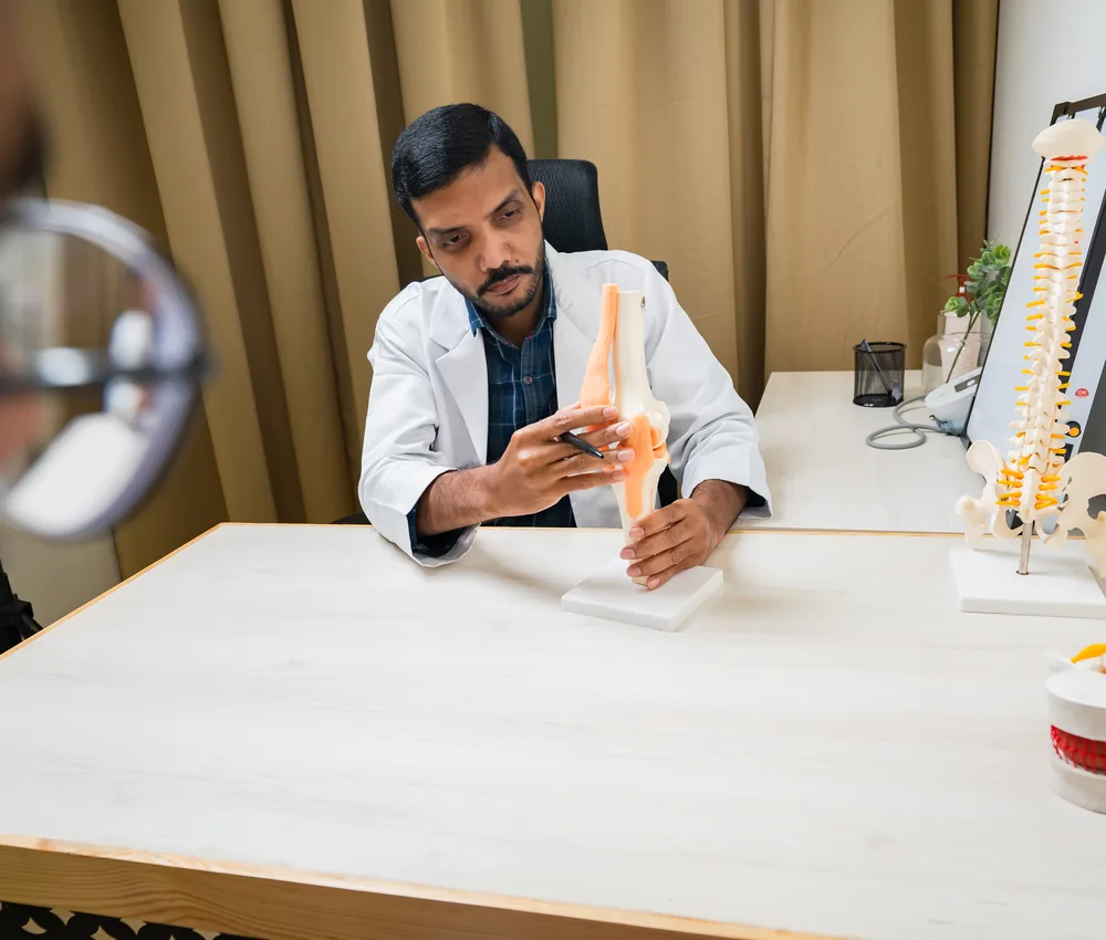 A doctor holding a spine model during a consultation