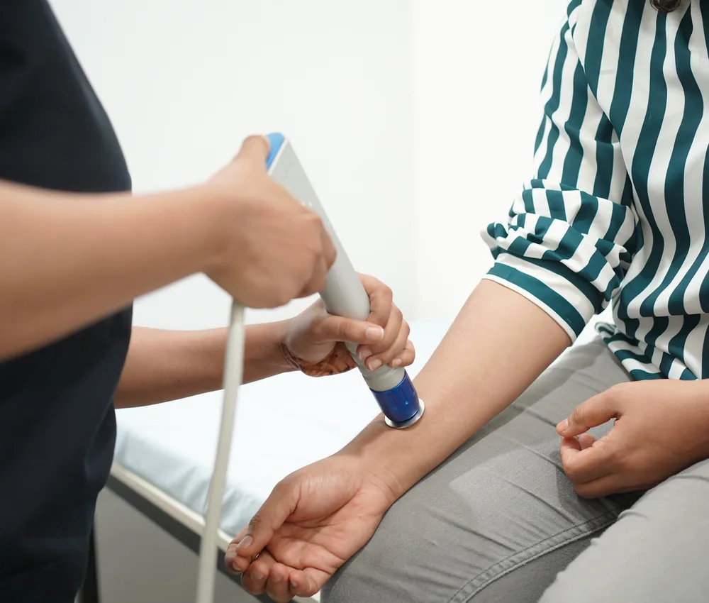 A shockwave therapy applicator being used on a patient's arm