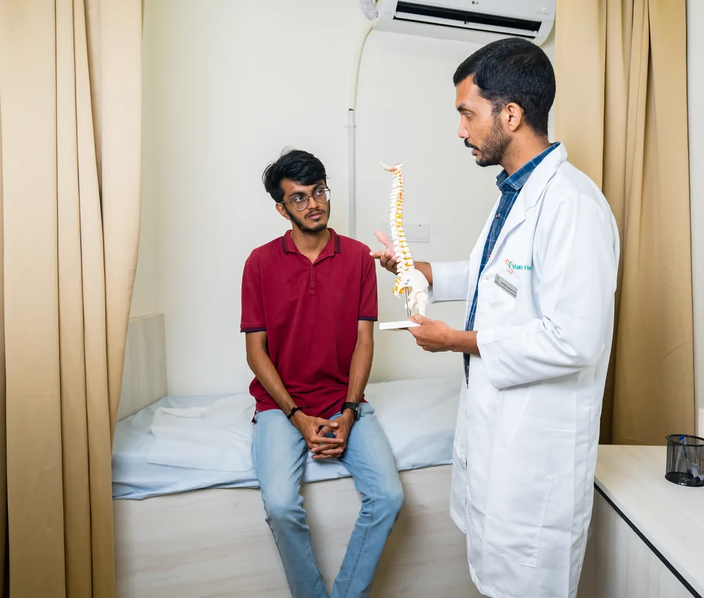A doctor holding a spine model during a consultation