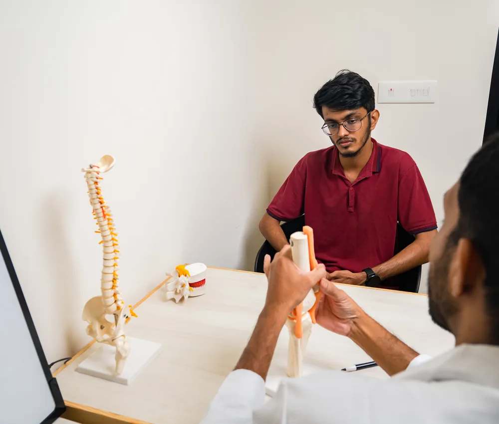 A doctor holding a spine model during a consultation