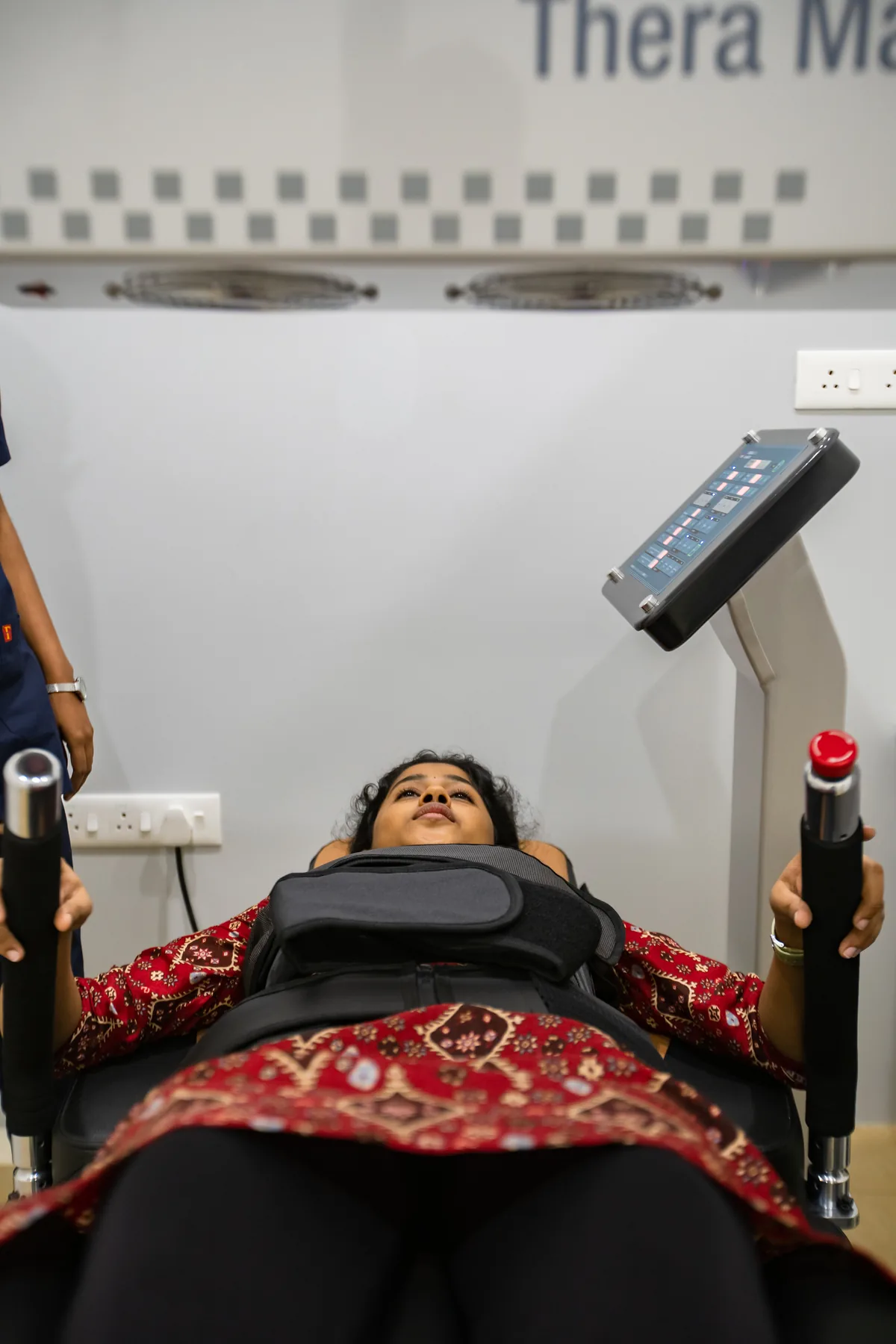 A patient on a spinal decompression system with a physiotherapist beside them