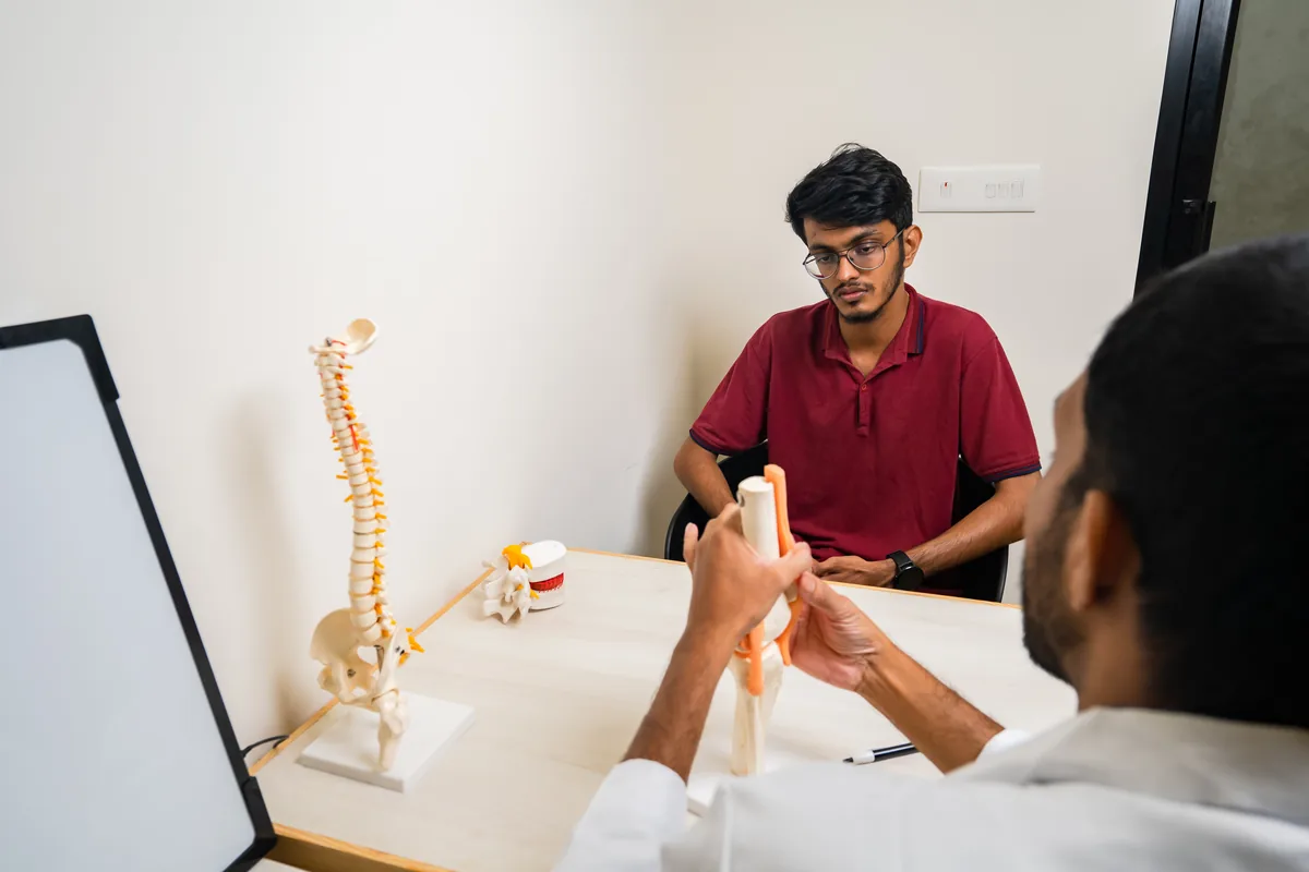 A doctor explaining a spine model to a patient