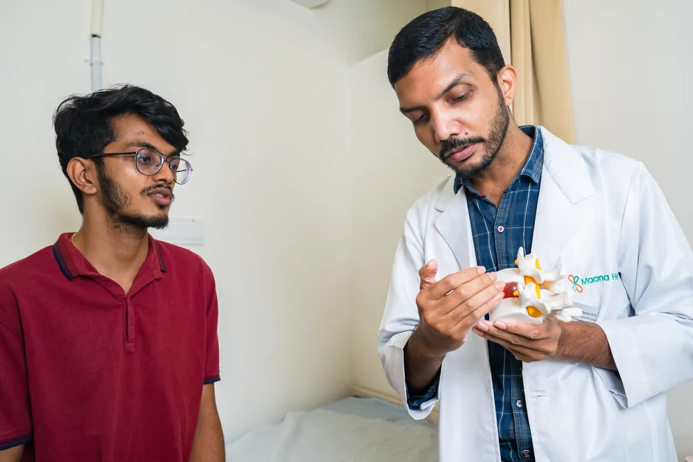 A doctor explaining a spine model to a patient at a spine assessment